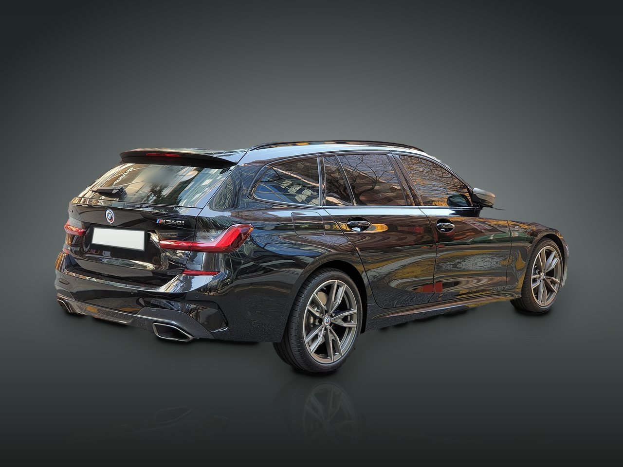 BMW M340i xDrive Touring preto no estúdio do stand, vista traseira de três quartos
